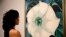 A Tate Modern representative poses for photographs next to "Jimson Weed/White Flower No.1" by American artist Georgia O'Keeffe at a press launch for her retrospective exhibition of over 100 works at the Tate Modern gallery in London, July 4, 2016. 