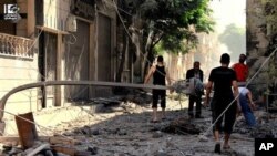 AP-authenticated citizen journalist photo shows Syrians inspecting rubble of damaged buildings due to government airstrike and shelling, al-Hamidiyyeh district, Homs, July 3, 2013.