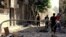 AP-authenticated citizen journalist photo shows Syrians inspecting rubble of damaged buildings due to government airstrike and shelling, al-Hamidiyyeh district, Homs, July 3, 2013.