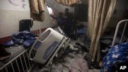 FILE - Palestinian paramedics inspect damage in the patient rooms caused by the Israeli strikes on the maternity ward at Nasser Hospital in the town of Khan Younis, southern Gaza Strip, Dec. 17, 2023.