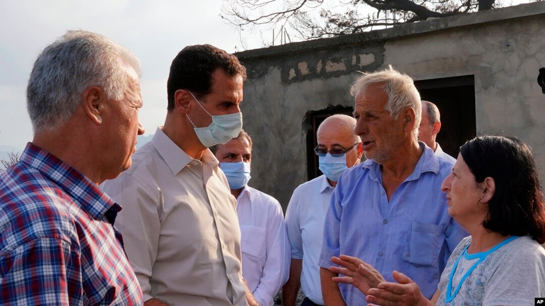 Presiden Suriah Bashar Assad (kedua dari kiri) mengenakan masker saat meninjau provinsi Latakia, Suriah, yang terdampak paling parah akibat kebakaran hutan, 13 Oktober 2020. (Facebook Presiden Suriah via AP).