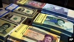 FILE - Iranian and U.S. banknotes are on display at a currency exchange shop in downtown Tehran, Iran.