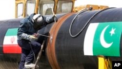 FILE - An Iranian worker welds two gas pipes at the beginning of construction of a pipeline to transfer natural gas from Iran to Pakistan, in southeastern Iran, near the Pakistani border, March 11, 2013. 