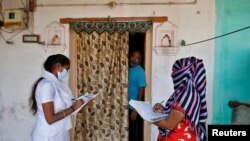 Pekerja kesehatan mengumpulkan data pribadi dari seorang pria sambil menyiapkan daftar saat survei dari rumah ke rumah untuk vaksinasi pertama Covid-19, di sebuah desa di pinggiran Ahmedabad, India, 14 Desember 2020. (Foto: Reuters)