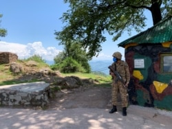 FILE - A Pakistan Army soldier stands guard at a hilltop post near the Line of Control (LoC) in Charikot Sector, Kashmir, July 22, 2020.