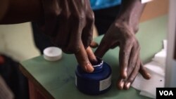 Un électeur se fait marquer le doigt après avoir voté à Freetown, en Sierra Leone, le 7 mars 2018. (VOA/Jason Patinkin)