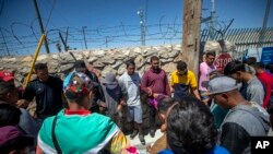 FILE— In this photo taken on Tuesday, May 9, 2023, migrants pray before turning themselves in to immigration authorities in downtown El Paso, Texas. As confusion explodes in El Paso, faith leaders continue to provide shelter, legal advice and prayer.