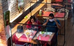 People eat lunch at a restaurant with plastic dividers between tables, as a preventative measure amid the COVID-19 pandemic, in Sao Paulo, Brazil, July 6, 2020.