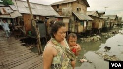 Seorang ibu menggendong anak balita menyeberangi jembatan di kawasan kumuh Muara Baru di Jakarta Utara (foto: dok).