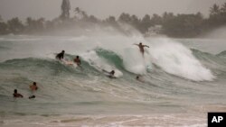 Surfistas tomando grandes olas generadas por el huracán Douglas en Laie Beach Park, el domingo 26 de julio de 2020, en Laie, Hawai.