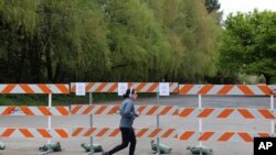 FILE - A woman jogs past a barricade outside a park in Salem, Oregon, April 15, 2020.