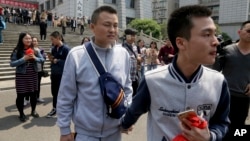 Sun Wenlin, right, and partner Hu Mingliang leave the court after a judge ruled against them in China's first gay marriage case in Changsha in central China's Hunan province, April 13, 2016. Several hundred supporters cheered them on at the courthouse.