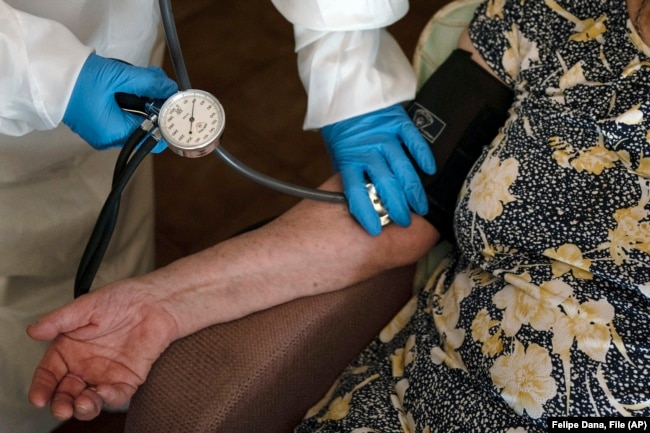 FILE - A doctor checks the blood pressure of A 94-year-old woman in Sant Sadurní d'Anoia, Catalonia region, Spain, Friday, July 31, 2020.