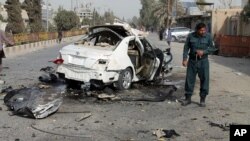 An Afghan policeman investigates a damaged car following a deadly bomb attack in Helmand province, southern Afghanistan, Nov. 12, 2020.