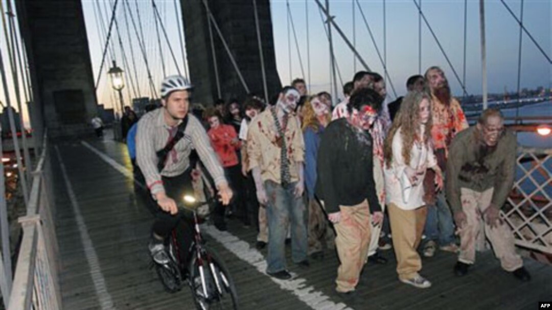 Biciklisti prolaze pored glumaca "zombija" na Bruklinškom mostu u Njujorku.