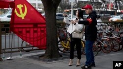 A deputized citizen gives direction to a resident near a Chinese Community Party flag on the streets of Beijing, China, Oct. 16, 2017.