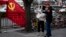 A deputized citizen gives direction to a resident near a Chinese Community Party flag on the streets of Beijing, China, Oct. 16, 2017.