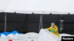 FILE - A person in personal protective equipment works to break down an area of The Samaritan's Purse Emergency Field Hospital in Central Park during the outbreak of the coronavirus disease (COVID-19) in New York City, May 9, 2020.