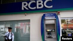 FILE - A security guard stands guard outside a branch of Rizal Commercial Banking Corporation (RCBC) in Paranaque city, Metro Manila, Philippines, Aug. 2 2016.