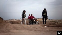 Kurdish female members of the Popular Protection Units check identifications of Kurdish men on a motorbike at a check point near the northeastern city of Qamishli, Syria, March 3, 2013. 