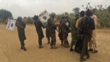 Abarwanyi ba Boko Haram bihishije amasura bariko bakira abanywanyi babo barekuwe, inyuma y'aho barekuriye abakobwa b'i Chibok 82 m'ukwezi kwa gatanu umwaka w'2017.