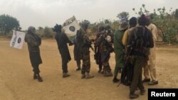 Abarwanyi ba Boko Haram bihishije amasura bariko bakira abanywanyi babo barekuwe, inyuma y'aho barekuriye abakobwa b'i Chibok 82 m'ukwezi kwa gatanu umwaka w'2017.