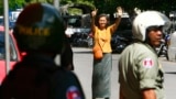 A Cambodian lawmaker from the main opposition party of Cambodia National Rescue Party (CNRP) Mu Sochua, center, gestures to make the number seven, the party's ballot number, before being detained by authorities at Freedom Park, in Phnom Penh, Cambodia, Tuesday, July 15, 2014. Three lawmakers from the opposition CNRP were detained and sent to police headquarters for leading about a hundred of their supporters to demonstrate in front of the park, asking authorities to open the site to the public. (AP Photo/Heng Sinith)