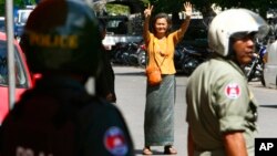 A Cambodian lawmaker from the main opposition party of Cambodia National Rescue Party (CNRP) Mu Sochua, center, gestures to make the number seven, the party's ballot number, before being detained by authorities at Freedom Park, in Phnom Penh, Cambodia, Tuesday, July 15, 2014. Three lawmakers from the opposition CNRP were detained and sent to police headquarters for leading about a hundred of their supporters to demonstrate in front of the park, asking authorities to open the site to the public. (AP Photo/Heng Sinith)