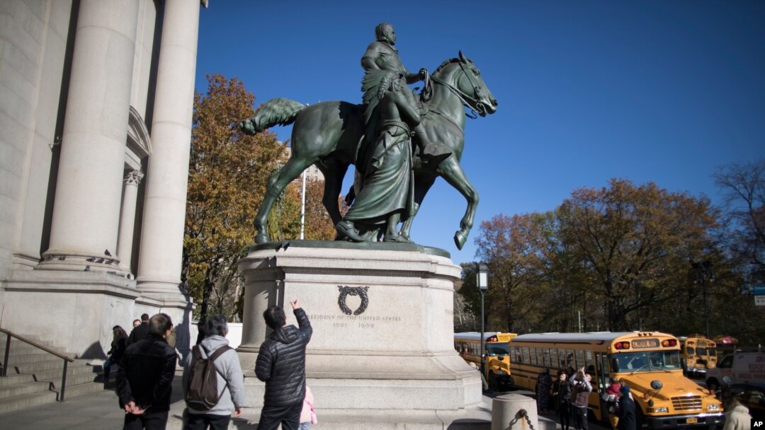 Visitors to the American Museum of Natural History in New York look at a statue of Theodore Roosevelt, flanked by a Native American man and African American man, Nov. 17, 2017.