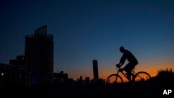 A man rides his bike along the seaside promenade as Beirut remains in darkness during a power outage, Aug. 19, 2021. Lebanon, mired in multiple crises, has faced months of severe fuel shortages.