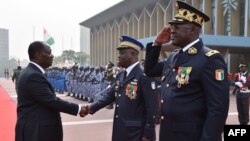 Le président ivoirien Alassane Ouattara, à gauche, salut le commandant en chef de la gendarmerie nationale ivoirienne, Nicolas Kouadio Kouakou, accompagné du directeur général de la police ivoirienne, Youssouf Kouyate, à droite, à Abidjan, le 4 janvier201