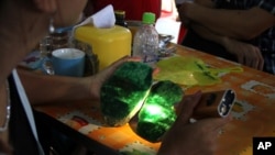 FILE - Local people examine the quality of a jade stone in the Hpakant area of Kachin state, northern Myanmar. 