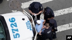 FILE - In this Tuesday, July 11, 2017 photo, New York City police officers detain and question a man in the Bronx borough of New York.