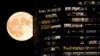 ARCHIVO - Una superluna pasa detrás de las ventanas iluminadas de un rascacielos en Nueva York, el 1 de agosto de 2023. 