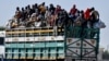 FILE - People who have fled their homes stand on a lorry at an Internally Displaced Persons camp in Maiduguri, Borno state, Nigeria, Nov. 30, 2021.