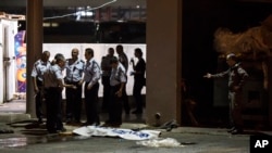 Israeli police stand by the shrouded body of Palestinian attacker in Beersheba, Israel, Oct. 18, 2015.