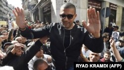 Le journaliste algérien Khaled Drareni est porté par des manifestants sur leurs épaules après avoir été brièvement détenu par les forces de sécurité dans la capitale algérienne Alger, le 6 mars 2020. (Photo by RYAD KRAMDI / AFP)
