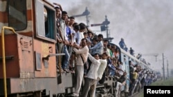 Penumpang bergelantungan di gerbong kereta yang sedang melaju di wilayah Utar Pradesh, India (Foto: dok) Kecelakaan kereta api sering terjadi di India.