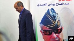 Mustafa Abdel Jalil, chairman of the Libyan National Transitional Council walks in front of a poster of slain Libyan rebels military commander General Abdel Fattah Younes after speaking at a news conference in Benghazi, Libya, August 9, 2011