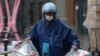 An Ele.me deliveryman wearing a face mask delivers food amid snowfall, at a shopping area on Valentine's Day in Beijing, Feb. 14, 2020.