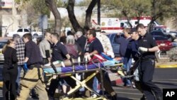Emergency personnel use a stretcher to carry a shooting victim outside a shopping center in Tucson, Arizona, 08 Jan 2011