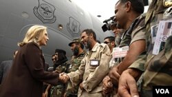 La secretaria de Estado, Hillary Clinton, saluda a los soldados del CNT, al descender del avión militar C-17 en el que viajó a Trípoli.