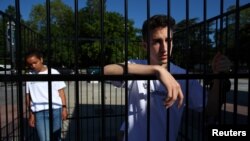 Los jóvenes dentro de la jaula llevaban camisetas que decían “#ClassroomsNotCages” (“Aulas, no jaulas”). Otros manifestantes llevaban carteles que decían “Los niños no deberían estar encerrados. Punto”.