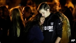 Hannah Schooping-Gutierrez, center, a student at Saugus High School, is comforted by her boyfriend Declan Sheridan, at right, a student at nearby Valencia High School during a vigil at Central Park, Nov. 14, 2019, in Santa Clarita, Calif.