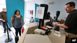 Immigrant and longtime resident in the United States Rosalva Mireles, left, is photographed and processed for her permanent driver's license at a Department of Motor Vehicles office, in Denver, Aug. 1, 2014. 