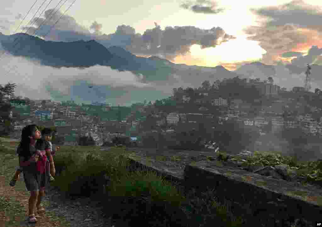 A Naga girl carries a child and walks up a slope during sunset in Kohima, capital of the northeastern Indian state of Nagaland.