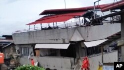 Tim penyelamat berjalan di samping gedung South Green Marketing tiga lantai yang runtuh di Padada, Provinsi Davao del Sur, Filipina selatan, Senin 16 Desember 2019. (Foto: AP)