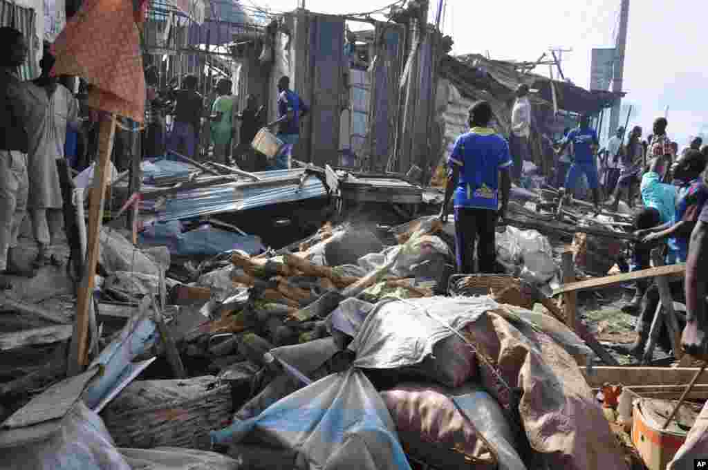 Mutane sun taru kusa da inda bam ya tashi cikin mota a kasuwar &quot;Monday Market&quot; ta Maiduguri, talata 1 Yuli, 2014. Mutane da dama sun mutu, akasarinsu mata tsoffi da almajirai dake bara.