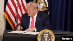 U.S. President Donald Trump signs executive measures for economic relief during a news conference amid the spread of the coronavirus disease, at his golf resort in Bedminster, N.J., Aug. 8, 2020. 