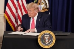 U.S. President Donald Trump signs executive measures for economic relief during a news conference amid the spread of the coronavirus disease, at his golf resort in Bedminster, N.J., Aug. 8, 2020.